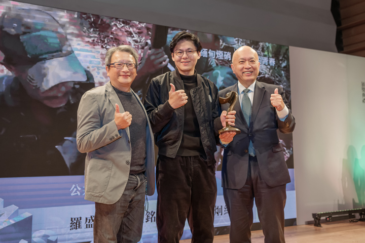 公視團隊以〈緬甸煙硝〉報導拿下國際新聞獎，公共電視攝影記者羅盛達（左起）、特約記者蘇威銘上台領獎，鄭家鐘擔任頒獎人。