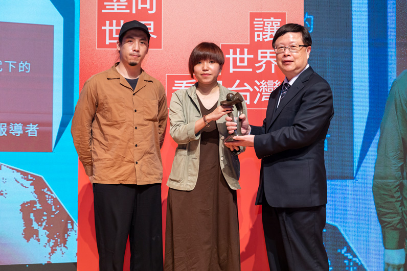 《報導者》記者陳德倫與美術設計江世民代表製作團隊上台領獎，陳德倫從頒獎人台灣期貨交易所董事長吳自心手中接下獎座。