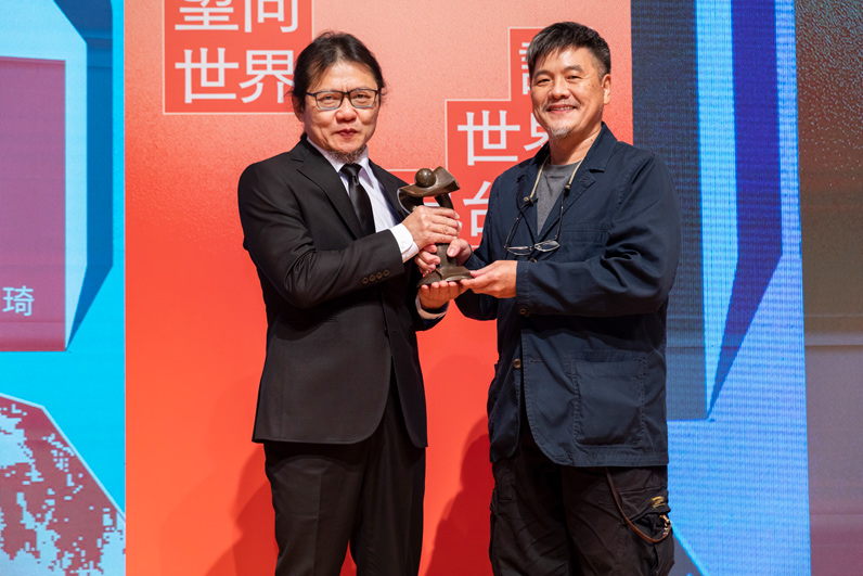 張乾琦(左)從新聞攝影類獎項評審劉振祥(右)手中接下獎座。 張乾琦(左)從新聞攝影類獎項評審劉振祥(右)手中接下獎座。
